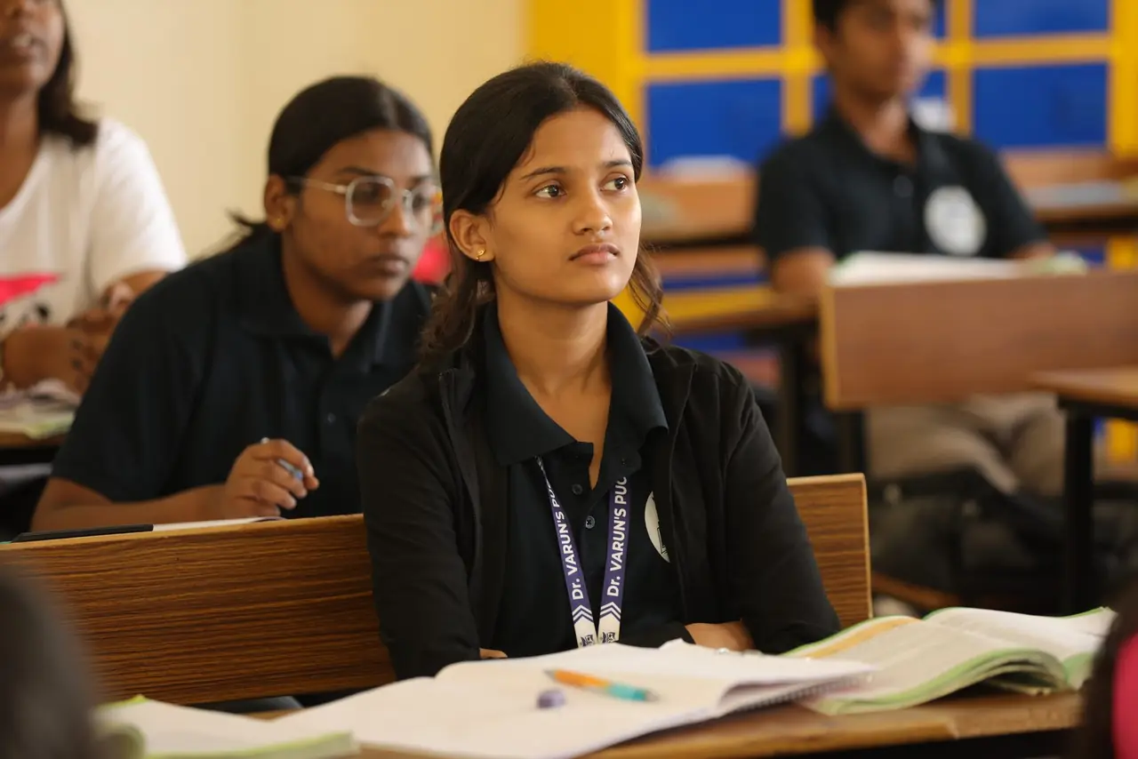 A student with an open notebook looking up at the teacher in a NEET class